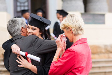 young female graduate hugging her father