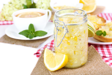 Tasty lemon jam with cup of tea on table close-up