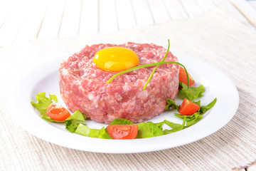 Delicious steak tartare with yolk on plate on table close-up