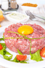 Delicious steak tartare with yolk on plate on table close-up