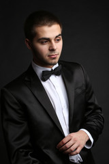 Handsome young man in suit on dark background