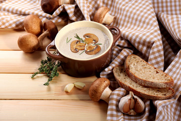 Mushroom soup in pot, on napkin,  on wooden background