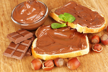 Bread with sweet chocolate hazelnut spread on wooden background