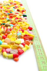 Measuring tape and pills, isolated on white. Dieting concept