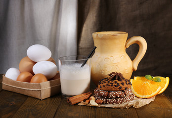 Eggnog with milk and eggs on table and fabric background