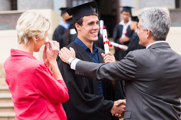 male graduate being congratulated by his father