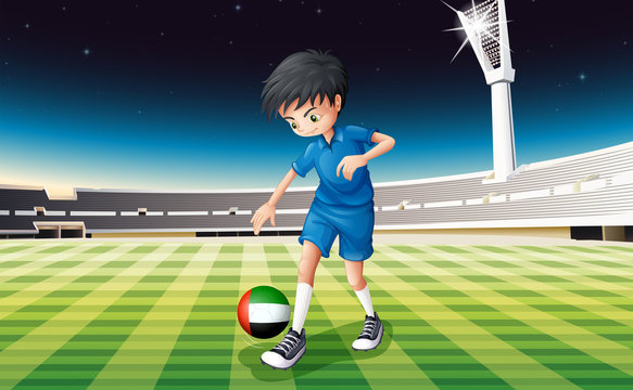 A boy kicking the ball with the United Arab Emirates flag