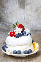 Meringue decorated with blueberries, strawberries and orange