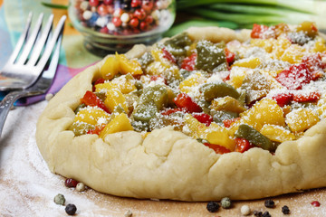 Vegetable galette on wooden kitchen board before baking.