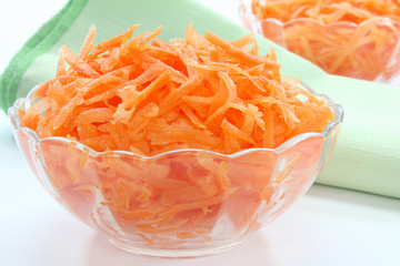 Raw grated carrots in glass bowl