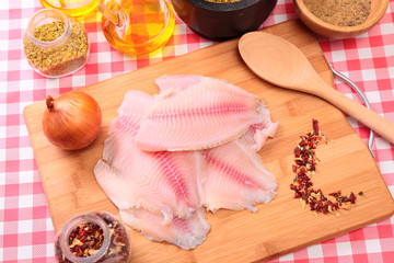 Raw fish tilapia on cutting board and spices