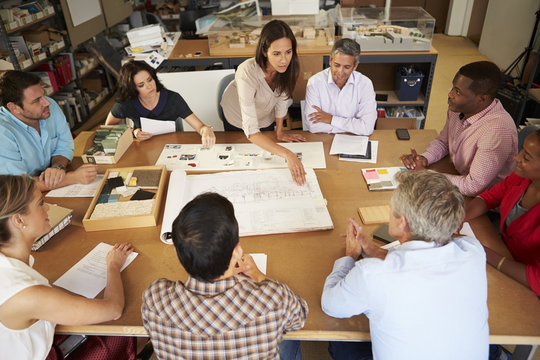Female Boss Leading Meeting Of Architects Sitting At Table - Powered by Adobe