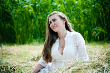 Young beautiful woman lying on hay one summer day