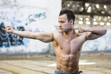 Muscular young man pointing with fingers to a side