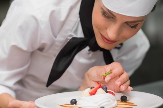 Smiling chef putting mint leaf on meringue dish
