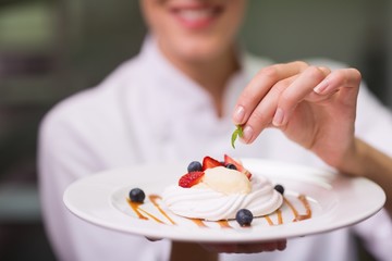 Happy chef putting mint leaf on dessert plate