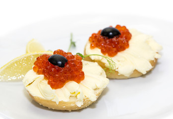 canape with red caviar and lemon on white background
