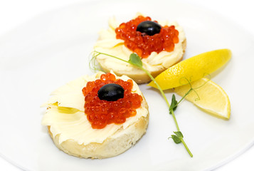 canape with red caviar and lemon on white background