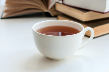 Cup of black tea and some books to read lying on the table