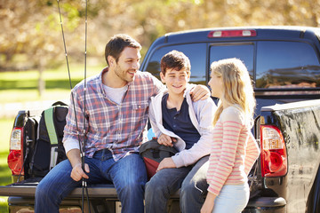 Father And Children Unpacking Truck On Camping Holiday