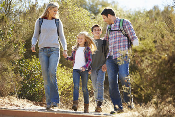 Family Hiking In Countryside Wearing Backpacks