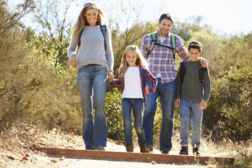 Family Hiking In Countryside Wearing Backpacks