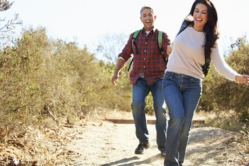 Couple Hiking In Countryside Wearing Backpacks