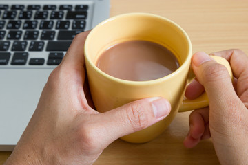 Coffee and a laptop on wooden desk