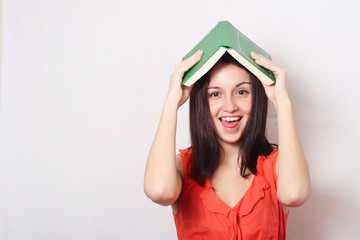 young smiling teenager girl holding books overhead .studio