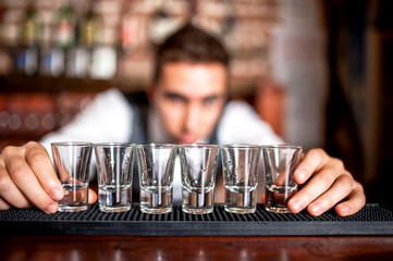 bartender preparing and lining shot glasses for alcoholic drinks