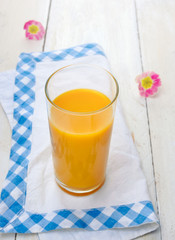 morning yellow juice on white table,blue cloth,pink flowers