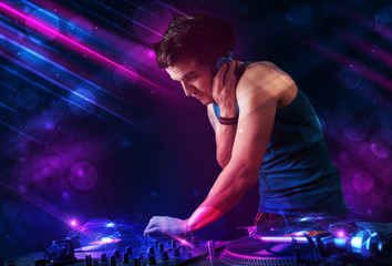 Plakat Young DJ playing on turntables with color light effects