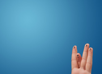 Happy smiley face fingers looking at empty blue background copy