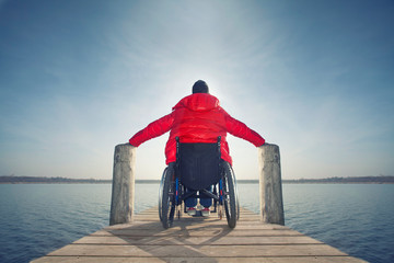 junger Mann im Rollstuhl am See