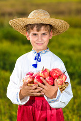 Happy farmer boy hold Organic Apples in Autumn Garden