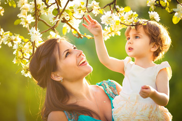 Happy woman and child in the blooming spring garden.
