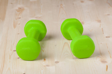 small green dumbbells on wooden surface