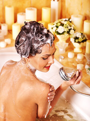 Woman washes her head at bathroom.