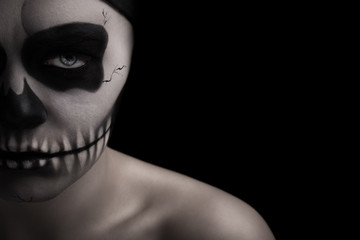 Low key portrait of young woman with skull make-up.