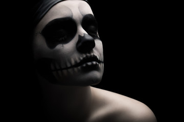 Low key portrait of young woman with skull make-up.