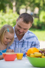 Family eating together outdoors at summer park or backyard