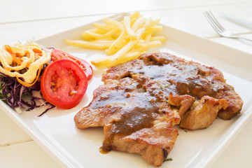 Grilled steak, French fries and  vegetables salad