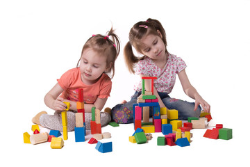 two girls playing with colorful wooden designer sitting