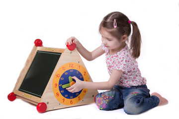 Girl studying while on toy hours sitting on the floor, on white