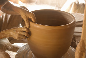 Potter's hands working on a pot at his pottery wheel