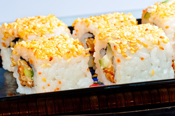 rolls with eel and sesame seeds on a black dish