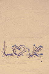 Love text wrote on white beach sand in vintage style