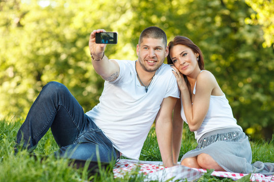 Beautiful young couple taking a self portrait in the park
