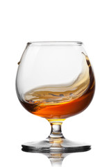 Splash of cognac in glass isolated on white background