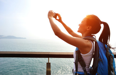 woman hiker taking photo at seaside 